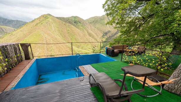 Une piscine sur le toit offrant une vue sur les montagnes, une terrasse en bois et du mobilier d’extérieur.