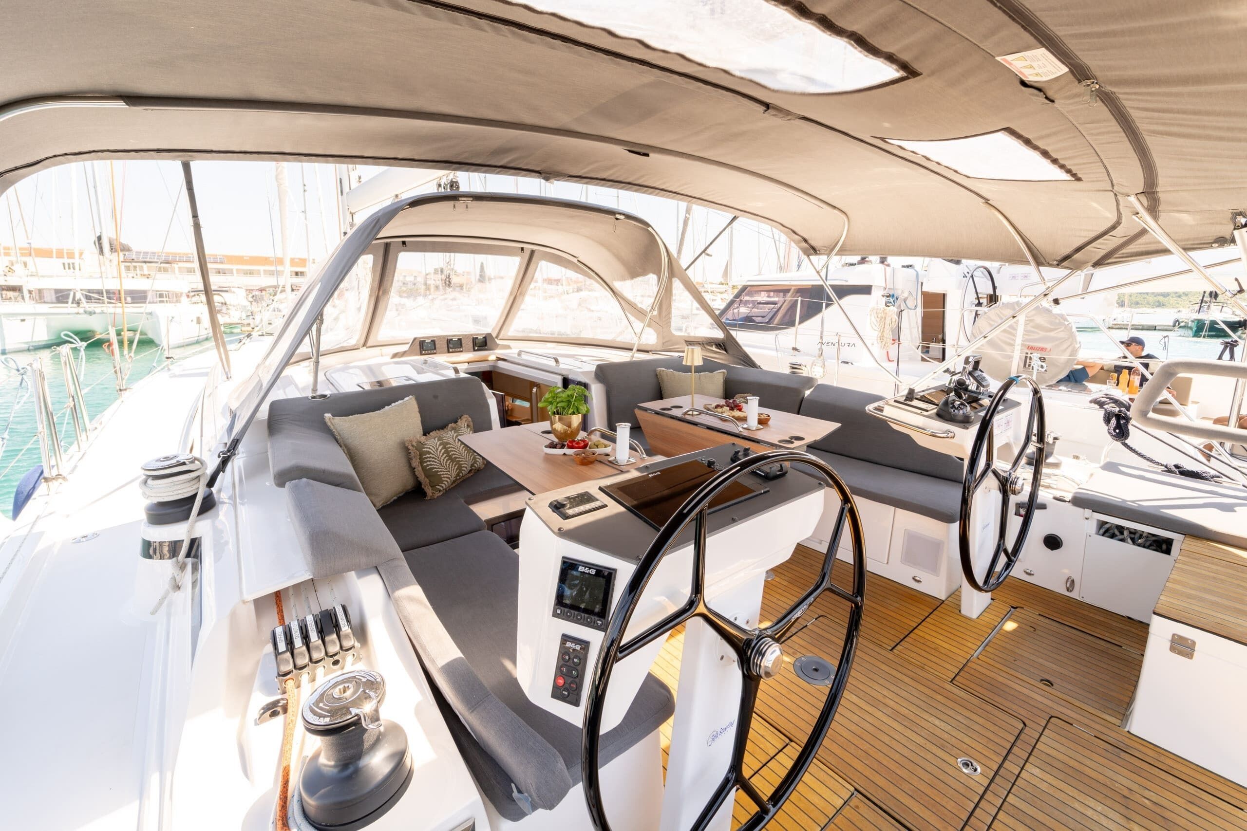 A yacht interior with a control station, seating area, and a view of the marina.