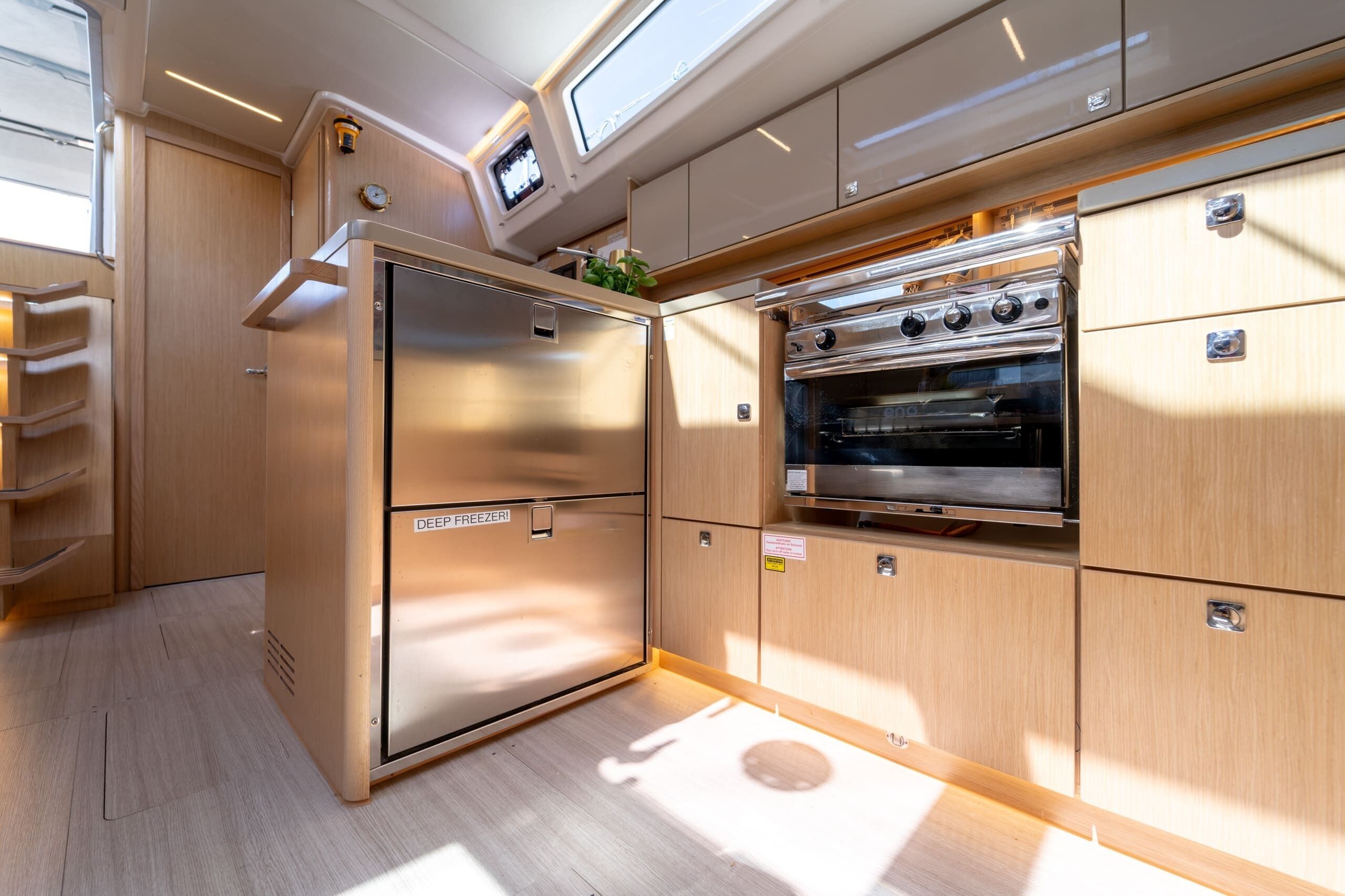 Una cocina compacta con refrigerador integrado, horno y una pequeña ventana sobre el horno.