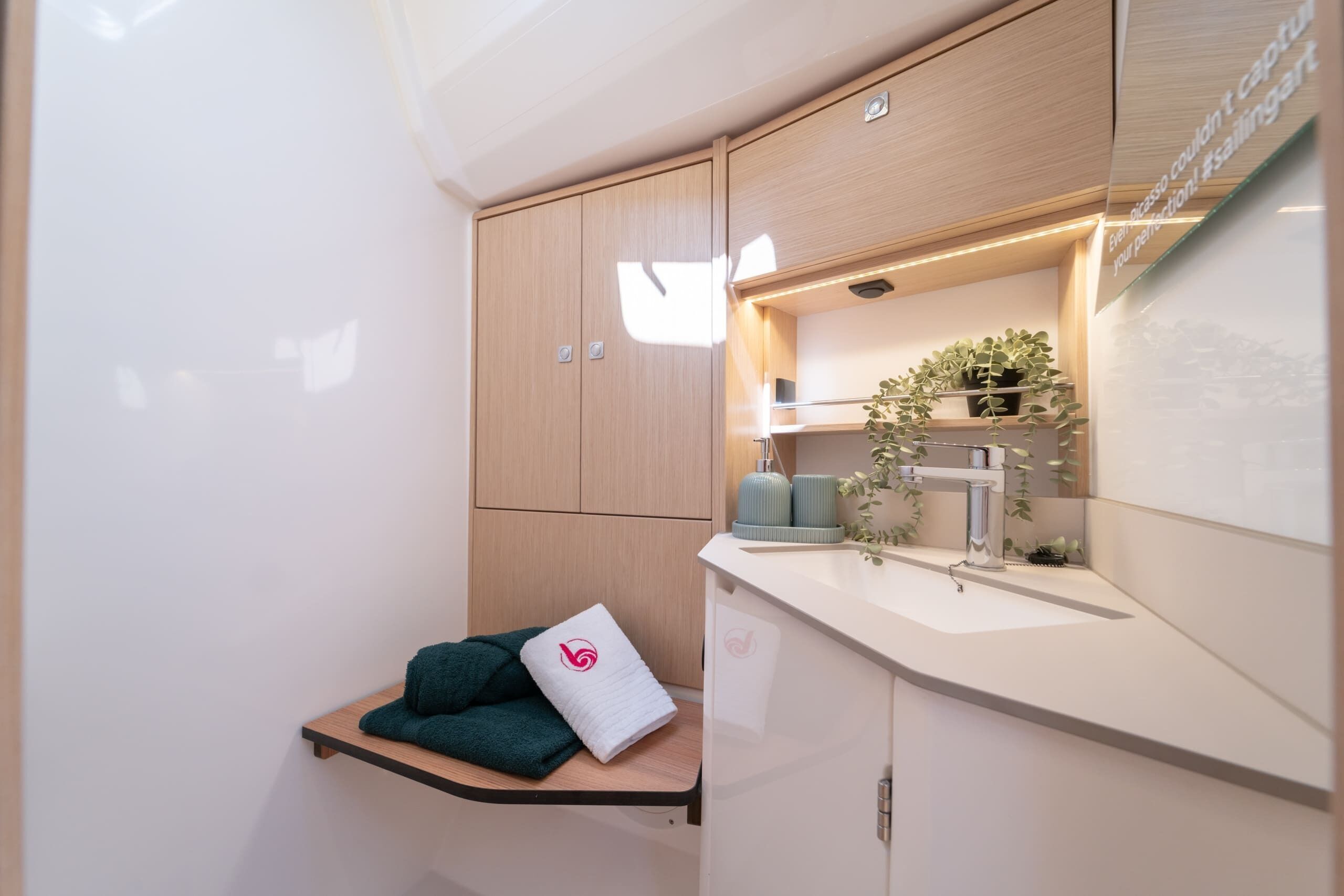 Une petite salle de bain avec un meuble en bois, une étagère avec des serviettes, un lavabo et un miroir.