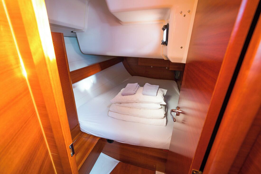 A compact, well-lit cabin with a bunk bed, a small table, and a wall-mounted storage unit.