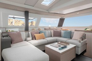 Ein modernes Yacht-Interieur mit Sofa, Couchtisch und großen Fenstern mit Meerblick.