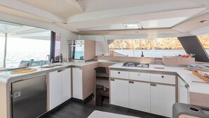 Uma cozinha moderna com vista para a água, forno embutido e área de jantar com mesa e cadeiras.