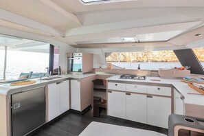 Eine moderne Küche mit Blick auf das Wasser, inklusive Backofen und einem Essbereich mit Tisch und Stühlen.