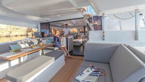 Interior moderno de iate com área de jantar, assentos e vista para a água.