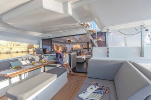 Ein modernes Jacht-Interieur mit Essbereich, Sitzgelegenheiten und Blick auf das Wasser.