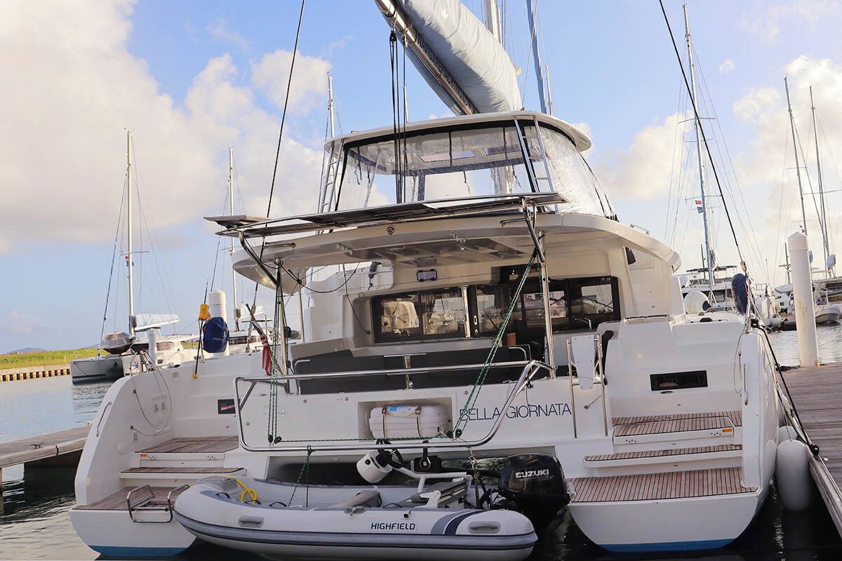 A white yacht named 'Bella Giornata' docked at a marina with multiple masts, a cabin with a view, and a 'Highfield' motor.
