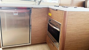 Eine kleine Küche mit Kühlschrank, Backofen und einem Fenster mit Blick nach draußen.