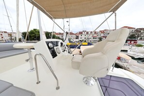 Das Bootsinnere zeigt ein Steuer, einen gepolsterten Sitz und ein Sonnendach.
