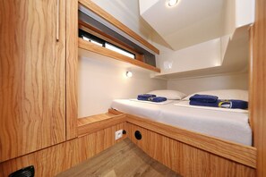 Habitación pequeña con literas, paredes de madera, un ventanal y una lámpara.