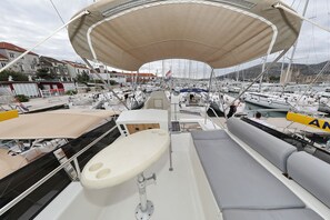 Ein Yachthafen mit mehreren angestaubten Booten, einem überdachten Sitzbereich und Blick auf Gebäude im Hintergrund.
