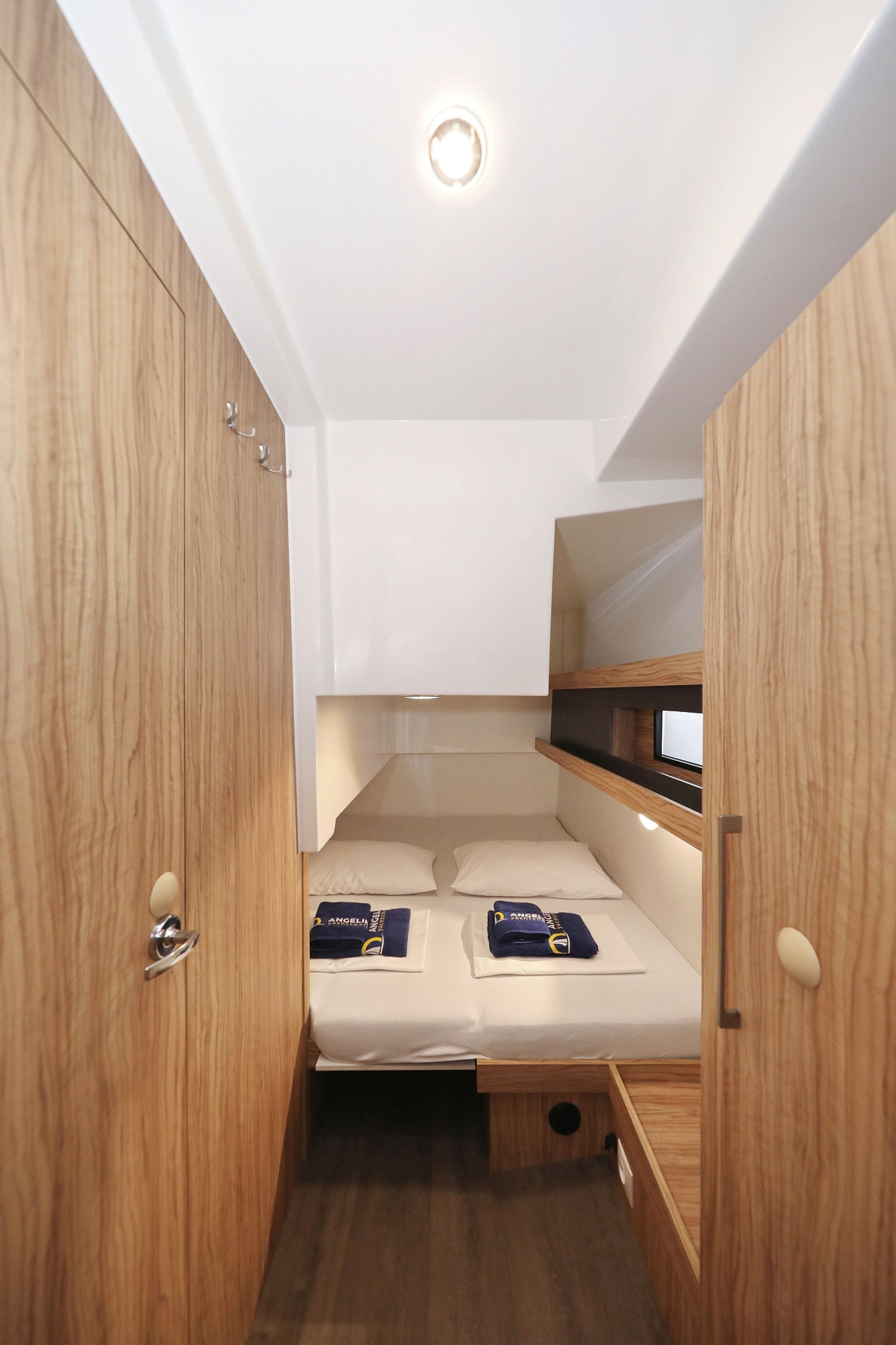 Ein kleiner, gut beleuchteter Raum mit Etagenbett, Holzschrank und einer kleinen Ablage.