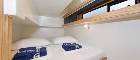 Una habitación pequeña con cama, ventana y un estante.