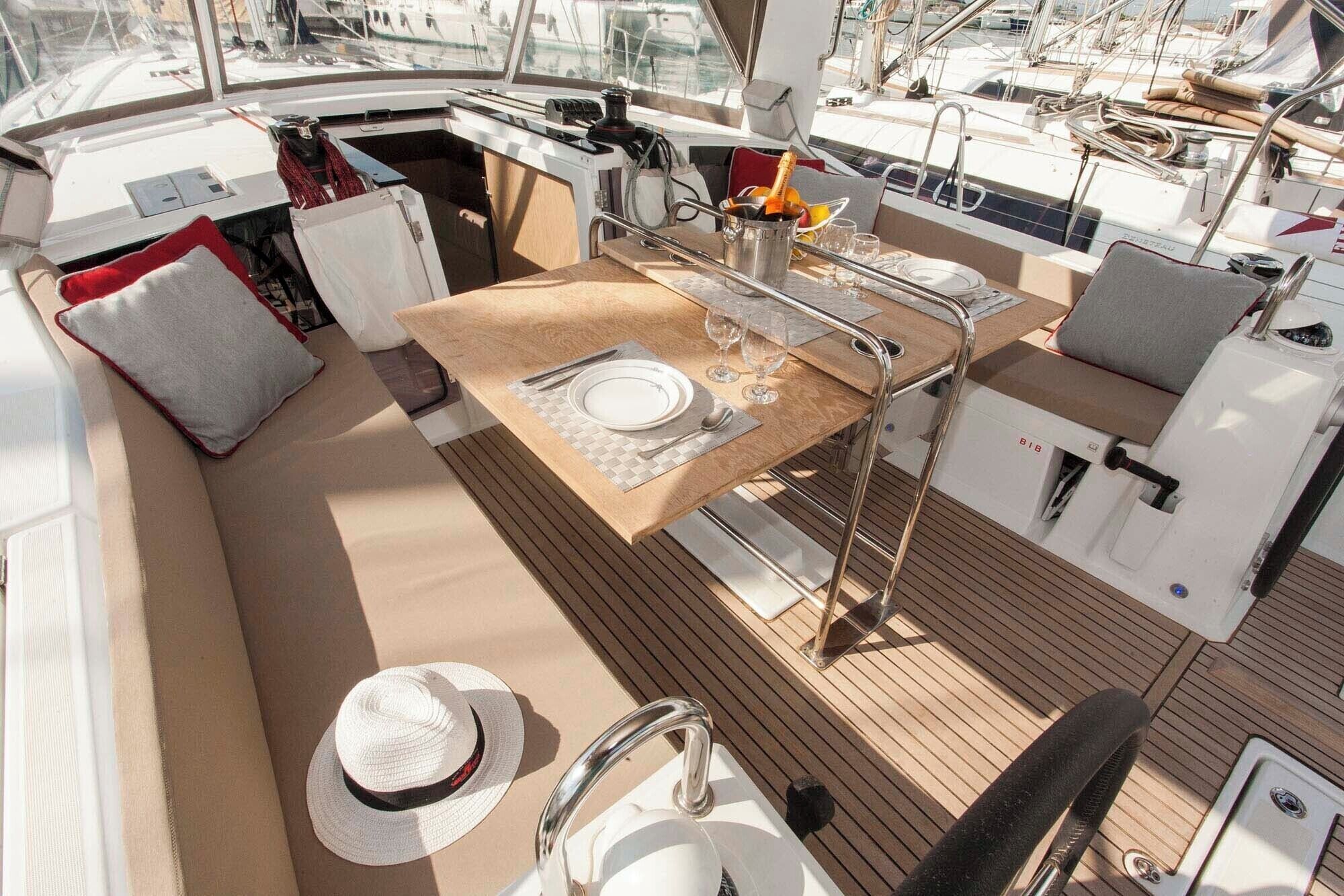A boat's deck with a dining area, a sink, and a hat.