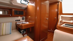 A compact interior with a wooden wardrobe, a small table with a radio, and a cushioned bench.