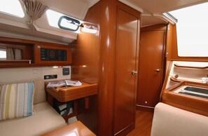 Um espaço interno compacto com um guarda-roupa de madeira, uma pequena mesa com um rádio e um banco estofado.