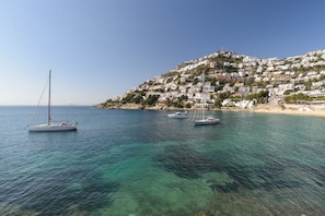 A coastal town with buildings on a hillside and sailboats on the water.