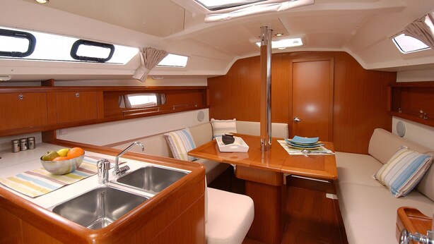 A compact kitchen with a sink, a bowl of fruit, and a small dining area with a table and chairs.