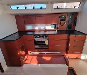 A compact kitchen with a stove, oven, and built-in microwave. There are cabinets and a countertop. - Sun-Kissed Sailing Adventure in Istria, Croatia (Pula)
