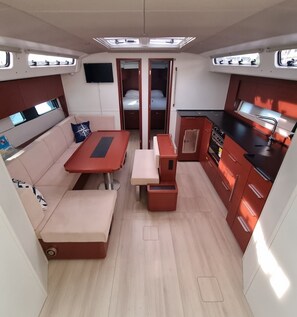 A compact interior with a sofa, a table, a kitchen area, and a small sleeping area. - Sun-Kissed Sailing Adventure in Istria, Croatia (Pula)