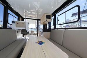 A modern interior with a central table, cushioned seating, and large windows. - Sibenik Sun and Beach Sailing Extravaganza: A Croatian Coastal Adventure (Vodice)