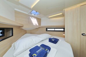 Ein gemütliches, helles Blockhaus mit Bett, kleinem Fernseher und Dachfenster.