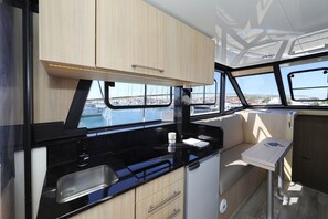 A compact galley with a sink, a small countertop, and a window with a view of a marina and buildings. - Sibenik Sun and Beach Sailing Extravaganza: A Croatian Coastal Adventure (Vodice)