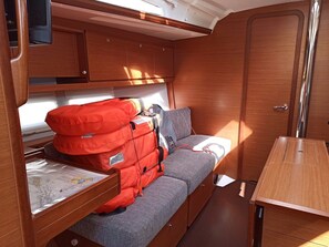Ein kompaktes Wohnmobil-Interieur mit einer Sitzecke, einem Tisch und einem Stauraum mit einer roten Tasche.