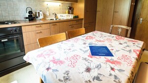 A kitchen with wooden cabinets, a stove, and a table with a floral tablecloth. - Bürcher Haus 1. OG Süd-West Appartement/Fewo, Dusche, WC by Interhome (Riederalp)
