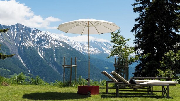A grassy area with a white umbrella, two lounge chairs, and a red box. - Bürcher Haus 1. OG Süd-West Appartement/Fewo, Dusche, WC by Interhome (Riederalp)