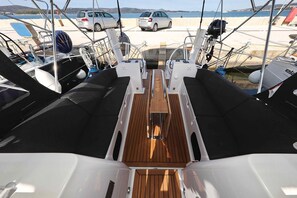 Ein Bootsdeck mit einer zentralen Holzvertäfelung, zwei seitlichen Sitzbereichen und einem Steuerlenkrad.