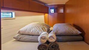 Une petite pièce agréable, dotée d’un lit, de coussins et d’un téléviseur fixé au mur.