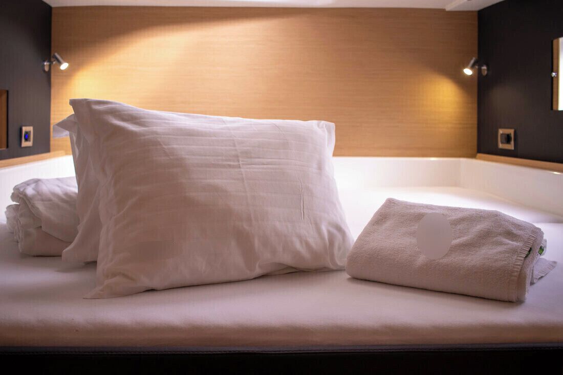 A neatly made bed with pillows and a folded towel in a hotel room.