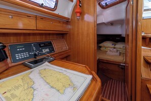 Uma cabana com interior de madeira, um painel de controle, um mapa e uma cama com toalhas dobradas.