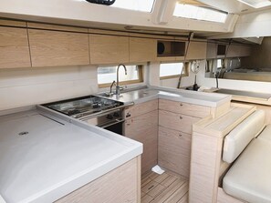 A compact galley kitchen with a stove, sink, and wooden cabinetry.