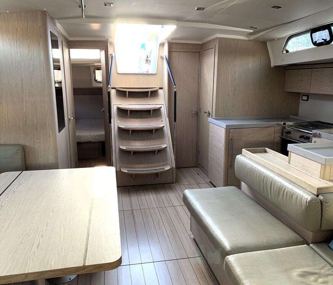 Un interior compacto con una mesa de comedor, un banco acolchado, una zona de cocina con estufa y un ventanal pequeño.