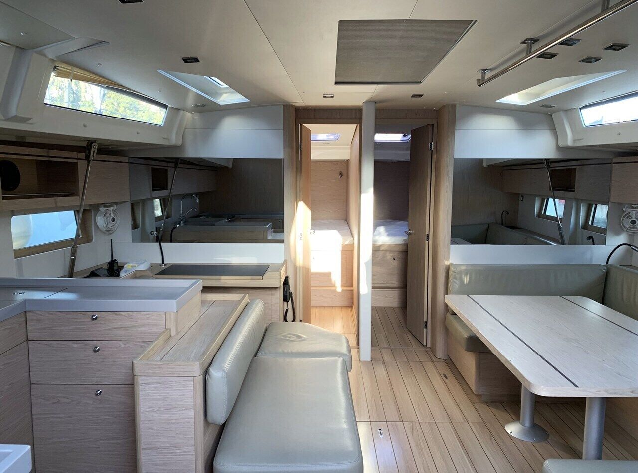 A compact, well-lit interior with a central seating area, a kitchenette, and a small bathroom.