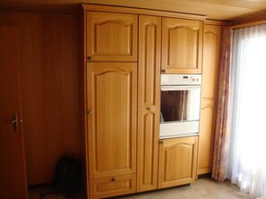 Ein Zimmer mit großem Holzschrank, fest eingebautem Backofen und einer Tür.