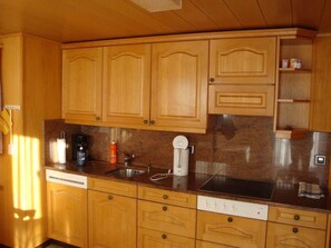 A kitchen with wooden cabinets, a dishwasher, and a coffee maker. - Abendrot 1. OG Süd-West Appartement/Fewo, Dusche oder Bad, WC by Interhome (Riederalp)