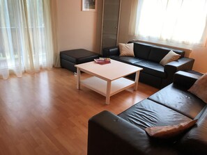 Ein Wohnzimmer mit einem schwarzen Ledersofa, einem weißen Couchtisch und einem schwarzen Hocker.