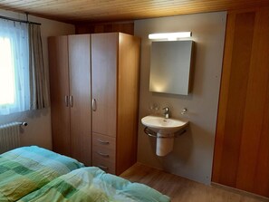 A bedroom with a bed, a wardrobe, a mirror, and a sink. - Abendrot 1. OG Süd-West Appartement/Fewo, Dusche oder Bad, WC by Interhome (Riederalp)