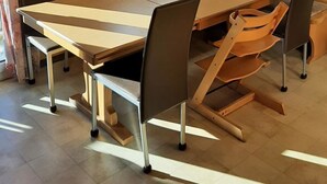 A dining area with a large wooden table, six chairs, and a window with curtains. - Abendrot 1. OG Süd-West Appartement/Fewo, Dusche oder Bad, WC by Interhome (Riederalp)