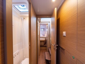 A narrow corridor with a skylight, wooden walls, a bench, and a visible bathroom with a sink and mirror. - Sun-Kissed Sailing Adventure in Split, Croatia (Split)