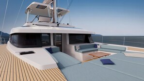 Le pont d’un yacht, avec des espaces aménagés pour s’asseoir, une table et une vue sur la mer.