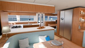 A modern kitchen with a view of the sea, a dining area with a table set for two, and a cozy seating area. - Sun-Kissed Sailing Adventure in Islas Sarónicas (Alimos)