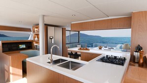 A modern kitchen with a view of the sea, a dining area, and a control panel. - Sun-Kissed Sailing Adventure in Islas Sarónicas (Alimos)