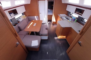 Ein kompaktes Wohnmobil-Interieur mit einer Küchenzeile, einer Essecke und einer Schlafliege.