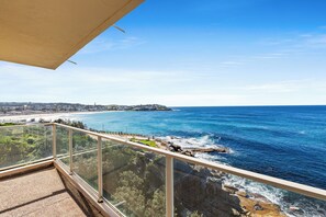 A balcony with a clear view of the ocean, rocky coastline, and distant buildings. - Oceanfront Bondi Escape with Spectacular Views (Bondi)