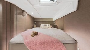 Un dormitorio moderno y funcional con cama, almohadas y mesita de noche.