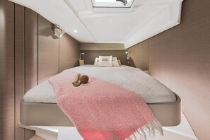 Ein kleines, modernes Schlafzimmer mit Bett, Kissen und Nachttisch.